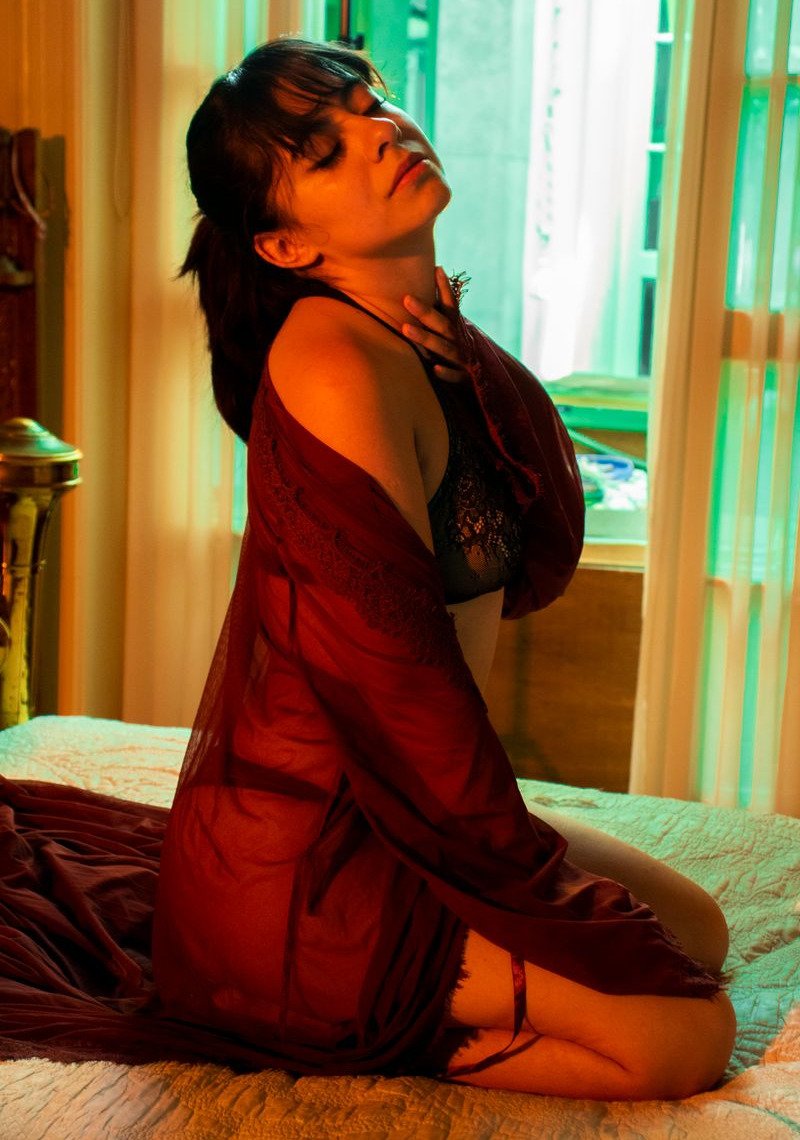 A creator by a curtained window in a darkened room
